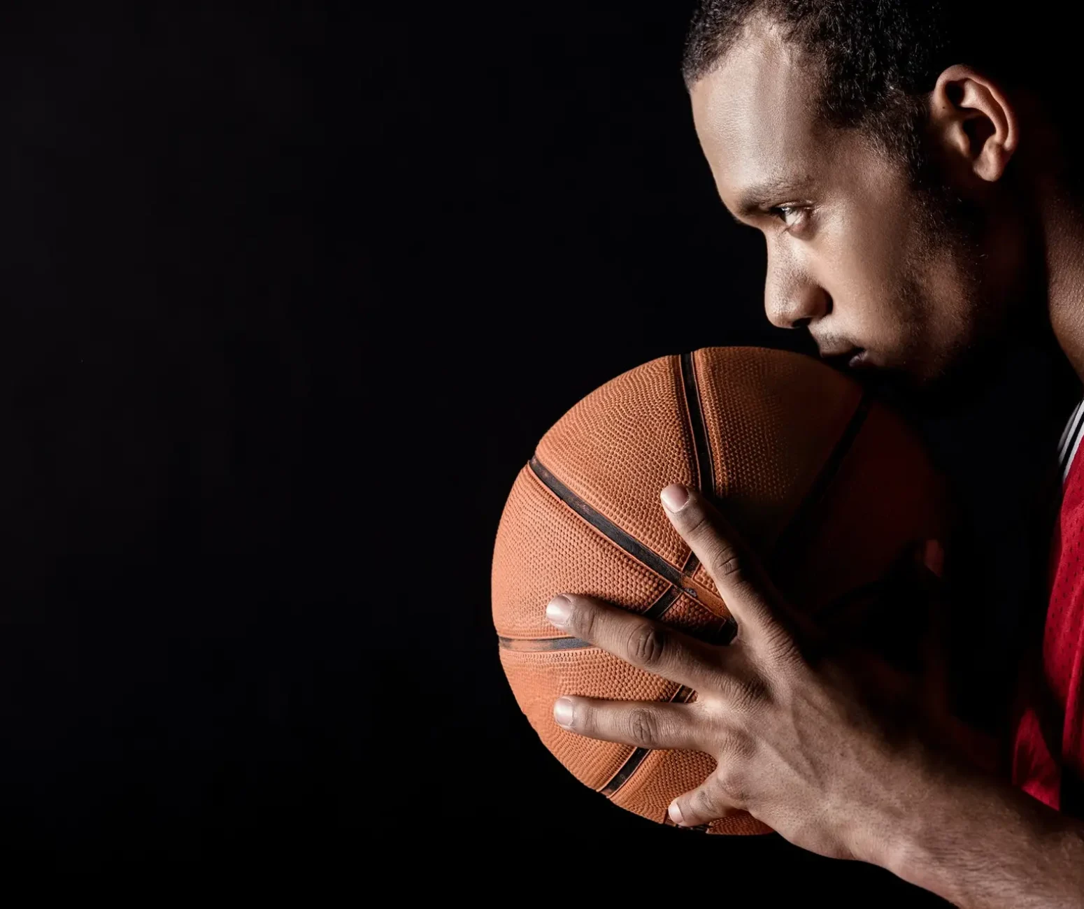 side-view-of-african-sporty-man-holding-basketball-ball-on-black